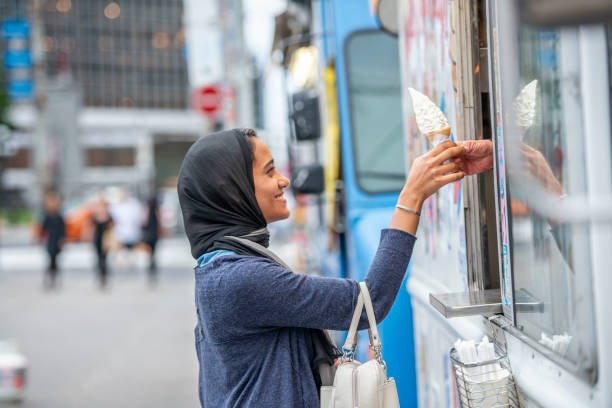 jeune femme musulmane, souriant tout en obtenant la crème glacée d’un camion dans la ville - camionnette de vendeur de glaces photos et images de collection