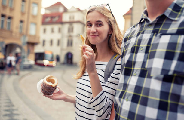 Woman enjoying the street food with boyfriend - holding Trdelnik (traditional Czech hot sweet pastry) Woman enjoying the street food with boyfriend - holding Trdelnik (traditional Czech hot sweet pastry) trdelník stock pictures, royalty-free photos & images