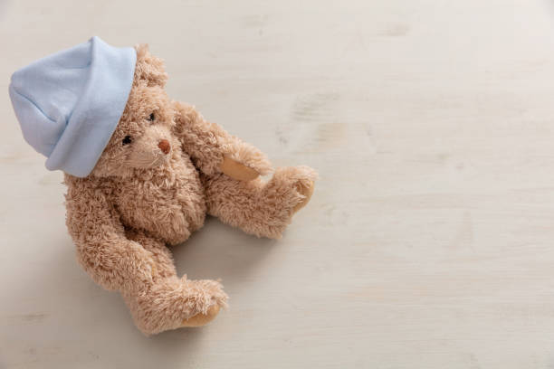 istock Teddy bear wearing pastel blue cap on wooden background, copy space 1032185804