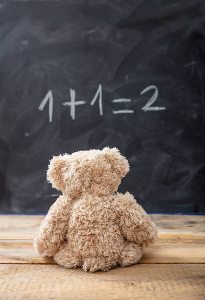школьный класс математики. тедди медведь глядя на простое уравнение на доске - mathematics mathematical symbol preschool simplicity стоковые фото и изображения