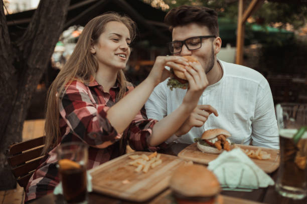 야외 레스토랑에서 햄버거를 먹고 행복 한 커플 - dining burger outdoors restaurant 뉴스 사진 이미지