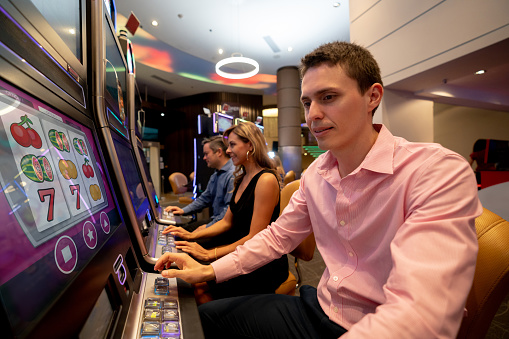 Group Of Latin American People Playing On Slot Machines At The Casino Stock Photo - Download Image Now - iStock