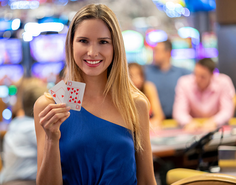 Beautiful latin american woman holding an ace and a ten at the casino while looking at camera smiling very happy