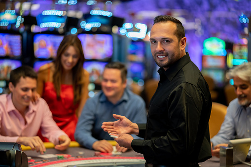 Portrait of card dealer at the casino looking at camera smiling very happy
