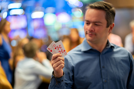 Adult man holding a ten and an ace looking at them smiling at the casino