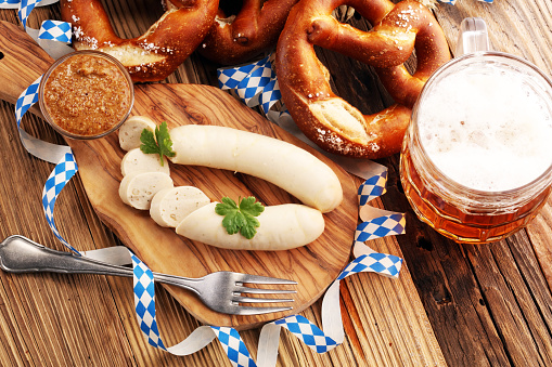 Bavarian veal sausage breakfast with sausages, soft pretzel and mild mustard on wooden board from Germany.