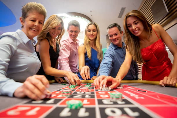 vista de ángulo bajo de personas apuestas en mesa de ruleta mirando muy emocionado - roulette table fotografías e imágenes de stock