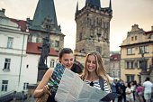 Young women standing on the Charles Bridge and exploring the city with city map