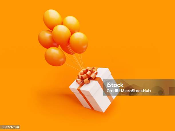 White Gift Box Tied With Orange Ribbon Is Carried Away By Orange Colored Balloons Stock Photo - Download Image Now