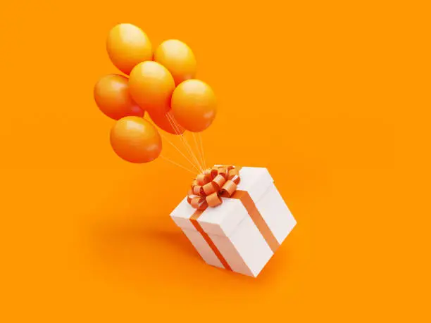 Photo of White Gift Box Tied with Orange Ribbon Is Carried Away By Orange Colored Balloons