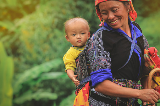 Mu cang chai, Vietnam-August 27, 2018: Smling Hmong tribe woman carrying her child in her backpack in Mu cang chai Northern Vietnam