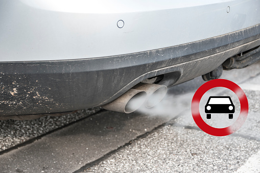 Doble escape de un coche con el humo y el tráfico de señal para la conducción de la prohibición, en alemán Fahrverbot para vehículos de motor diesel en zonas de bajas emisiones de algunas ciudades en Alemania photo
