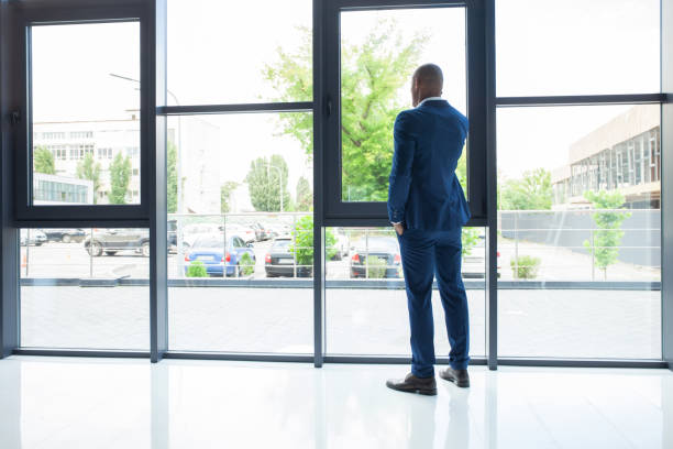 istock Black American Businessman Standing at the window, Calling Someone Through Mobile Phone. 1032236070