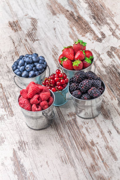 istock Berries fresh arrangement in tin cans on white wooden table 1032236636
