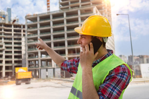 istock Young Engineer talking with smartphone on construction site and crane background. 1032283990