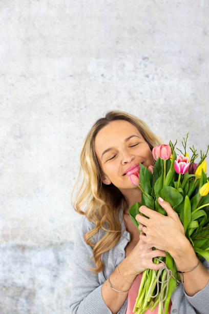 istock Woman Holding Flowers Against Wall 1032285584