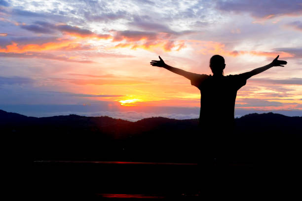 the woman stretches out her hands to the sun at sunset or dawn stock photo