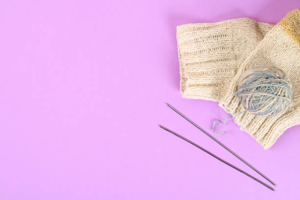 istock A ball of wool with knitting needles and knitted socks on a color pastel table. Needlework. 1032306178