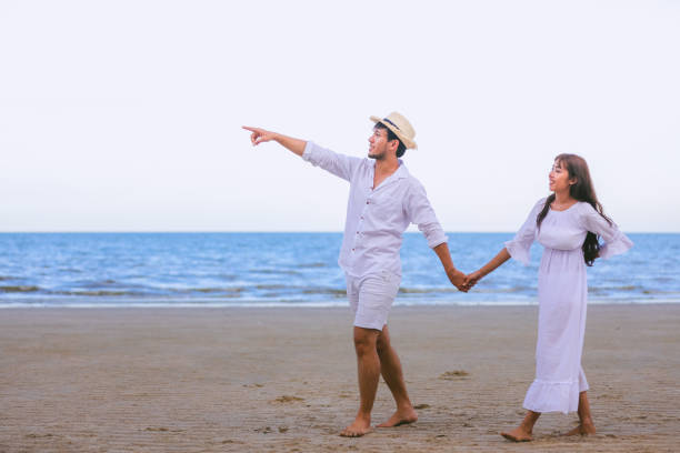 istock Couple Holding Hands While Walking At Beach Against Sky 1032306250