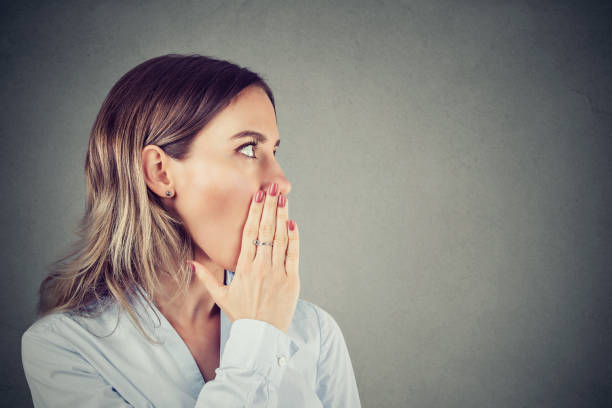 istock woman whispering private information a secret 1032330718