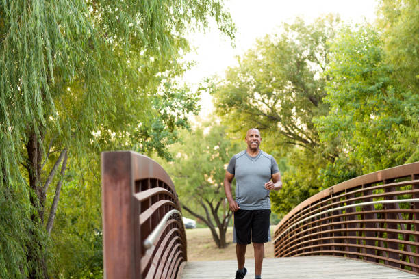 uomo afroamericano che cammina nel parco. - running jogging african descent nature foto e immagini stock