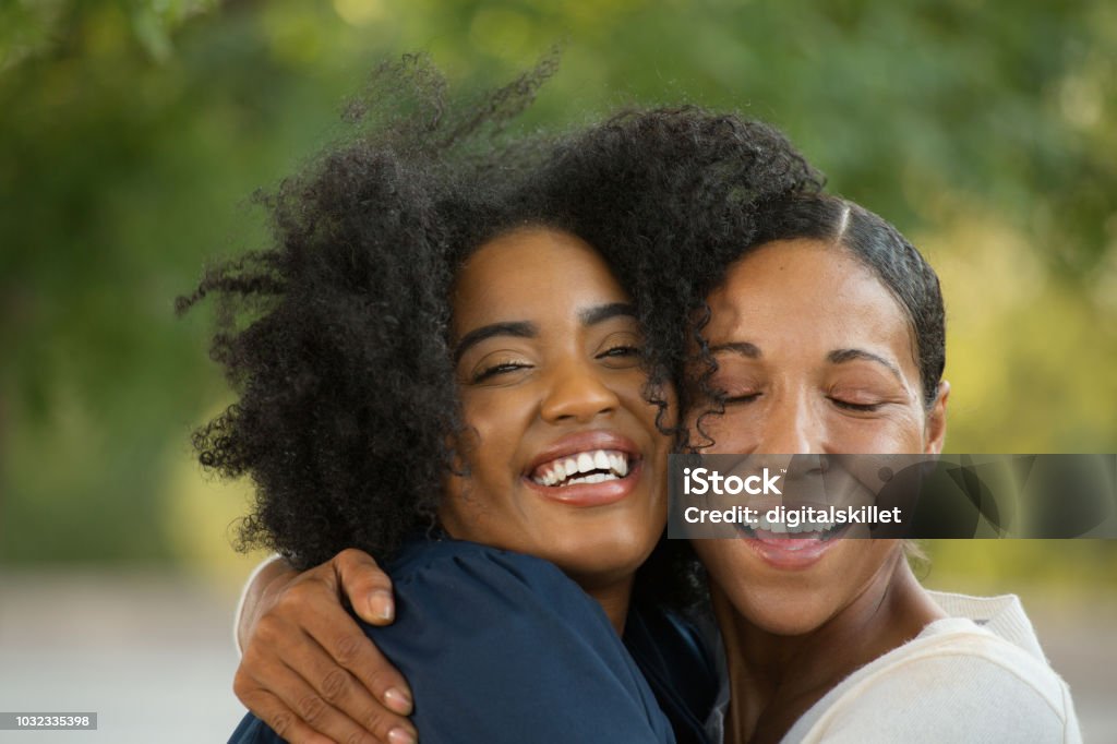 Mother hugging her daughter at her graduation. African American mother hugging her daughter at her graduation. Mother Stock Photo