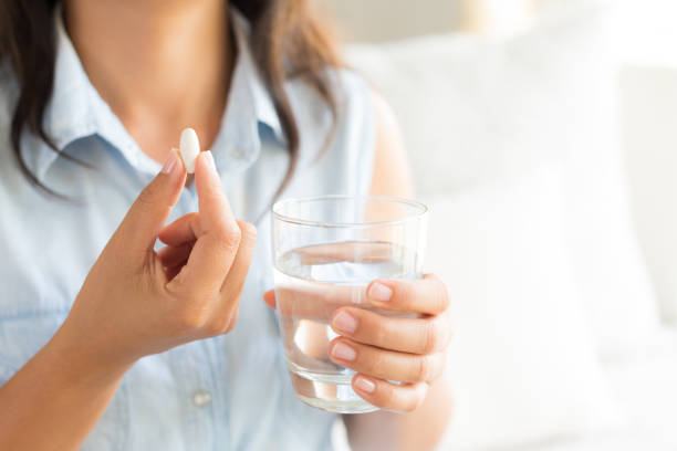알 약 정제 및 두통 치료에 대 한 물의 유리 근접 촬영 여자 핸드. 의료, 의료 개념을 보충합니다. - capsule pill white nutritional supplement 뉴스 사진 이미지