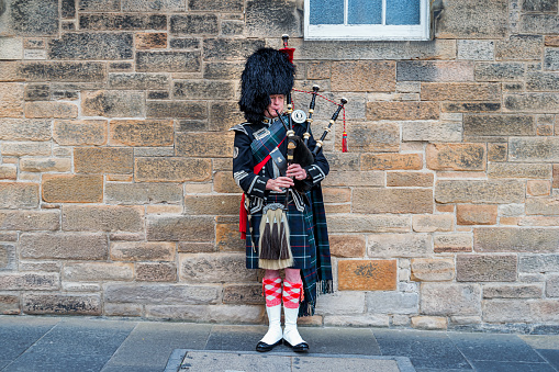 Scottish Piper plays on the Royal Mile in old town Edinburgh, Scotland, UK.