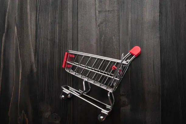 close-up of shopping trolley on darkwood background with some copy space