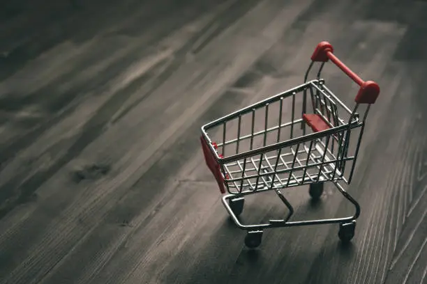 close-up of shopping trolley on darkwood background with some copy space