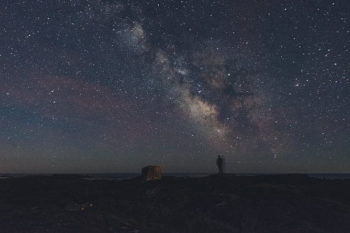 A person motions on a hilltop under the Summer Milky Way.  Long exposure.