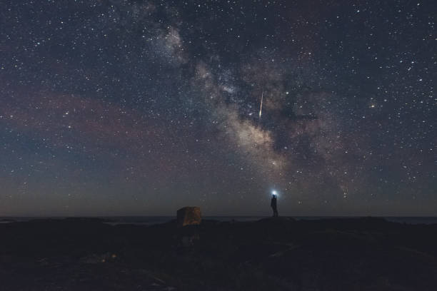 Photographing a Meteor A man photographs a bright meteor with a smart phone. Long exposure. meteorite photos stock pictures, royalty-free photos & images