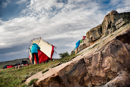 Back view of a senior aged woman taking apart her tent on a backpacking camping trip in the Grenadier Mountains, Continental Divide, San Juan National Forest, Rocky Mountains, Silverton, CO, USA