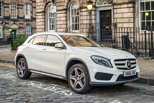 A white Mercedes GLA 250 is parked on a cobbled street in the New Town district of downtown Edinburgh, Scotland, UK.