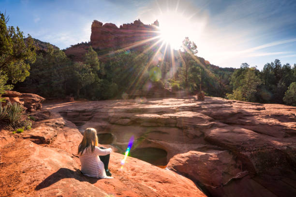 Girl sitting at Seven Sacred Pools, Sedona A blond teenage girl sits facing the sun on the rocks overlooking the Seven Sacred Pools, Sedona, Arizona, USA sedona photos stock pictures, royalty-free photos & images
