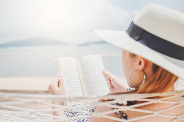 istock Woman reading a book on hammock beach in free time summer holiday 1032425998