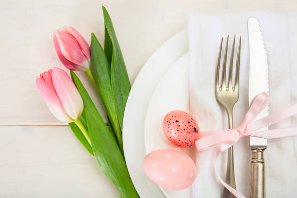 istock Easter table setting with pink tulips on white wooden background. Top view 1032454808