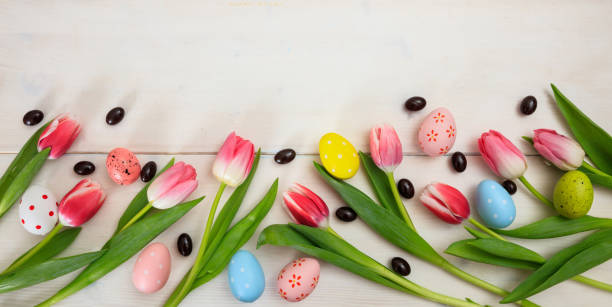 istock Easter concept. Pink tulips and easter eggs on white wooden background, copy space, top view, banner 1032454824