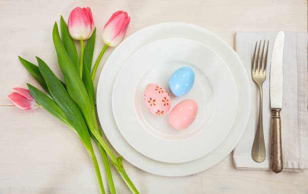 istock Easter table setting with pink tulips on white wooden background. Top view 1032454832