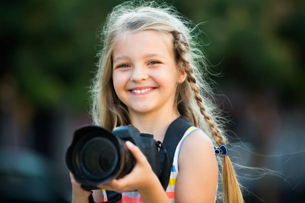 istock cheerful female child taking pictures with camera in park 1032473082