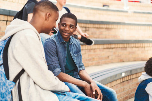 istock Smiling friends sitting on steps at school campus 1032473238