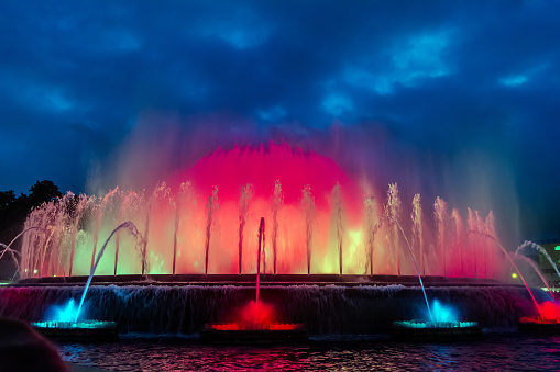 Colorful performance of Magic Fountain of Montjuic in Barcelona, Spain. Show combines a spectacular display of music, water acrobatics and lights which generate over 50 kinds of shades and hues.