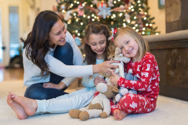 istock Mom laughs with her two daughters in front of the Christmas tree 1032486614