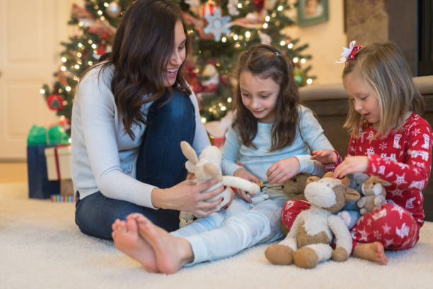 istock Mom laughs with her two daughters in front of the Christmas tree 1032486646