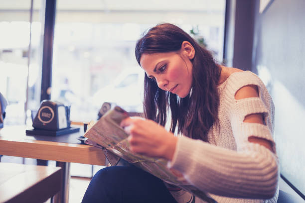 istock Young woman, reading newspapers, sitting in cafe 1032490106