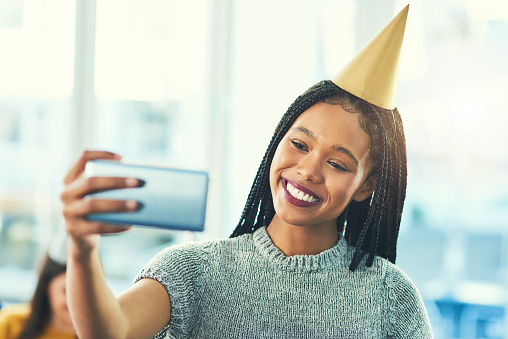 Cropped shot of an attractive young woman taking selfies while celebrating a birthday with her friends
