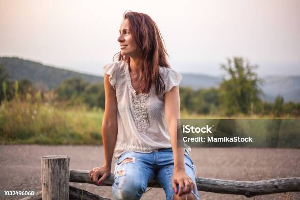 Profile Of A Mature Woman Sitting On A Wooden Fence In Nature Stock Photo - Download Image Now