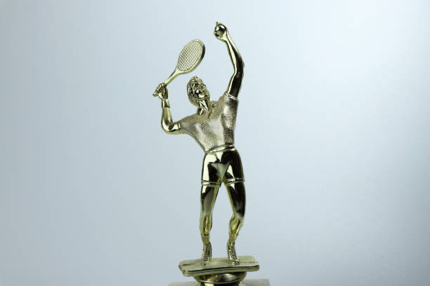 A golden cup for winner in tennis tournament. Beautiful golden tennis player stock photo