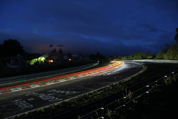 Racing car lights Nürburgring 24h race at the Nürburgring long exposure at the Schwalbenschwanz bend In the blue hours right before dawn the 24h endurance race at the Nürburgring is at halftime. The drivers need to adopt to the changing light and track conditions and fight the desire for sleep. nürburgring stock pictures, royalty-free photos & images