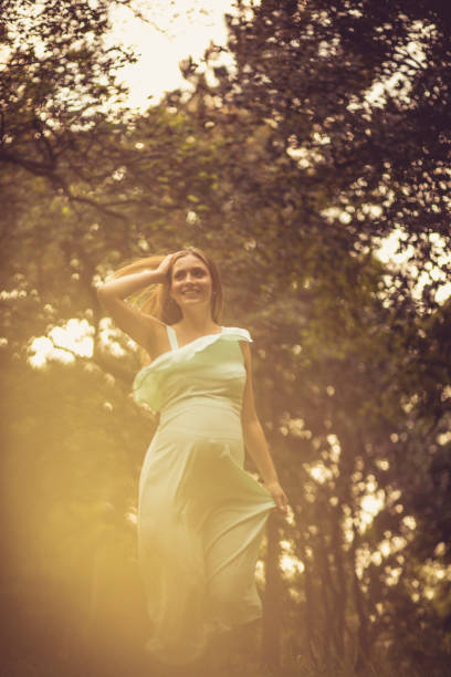 Sun gives a new life. Pregnant smiling woman spending time in nature. Copy space.